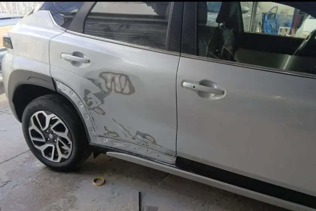 Camioneta plata con el costado trasero golpeado, antes de la reparación